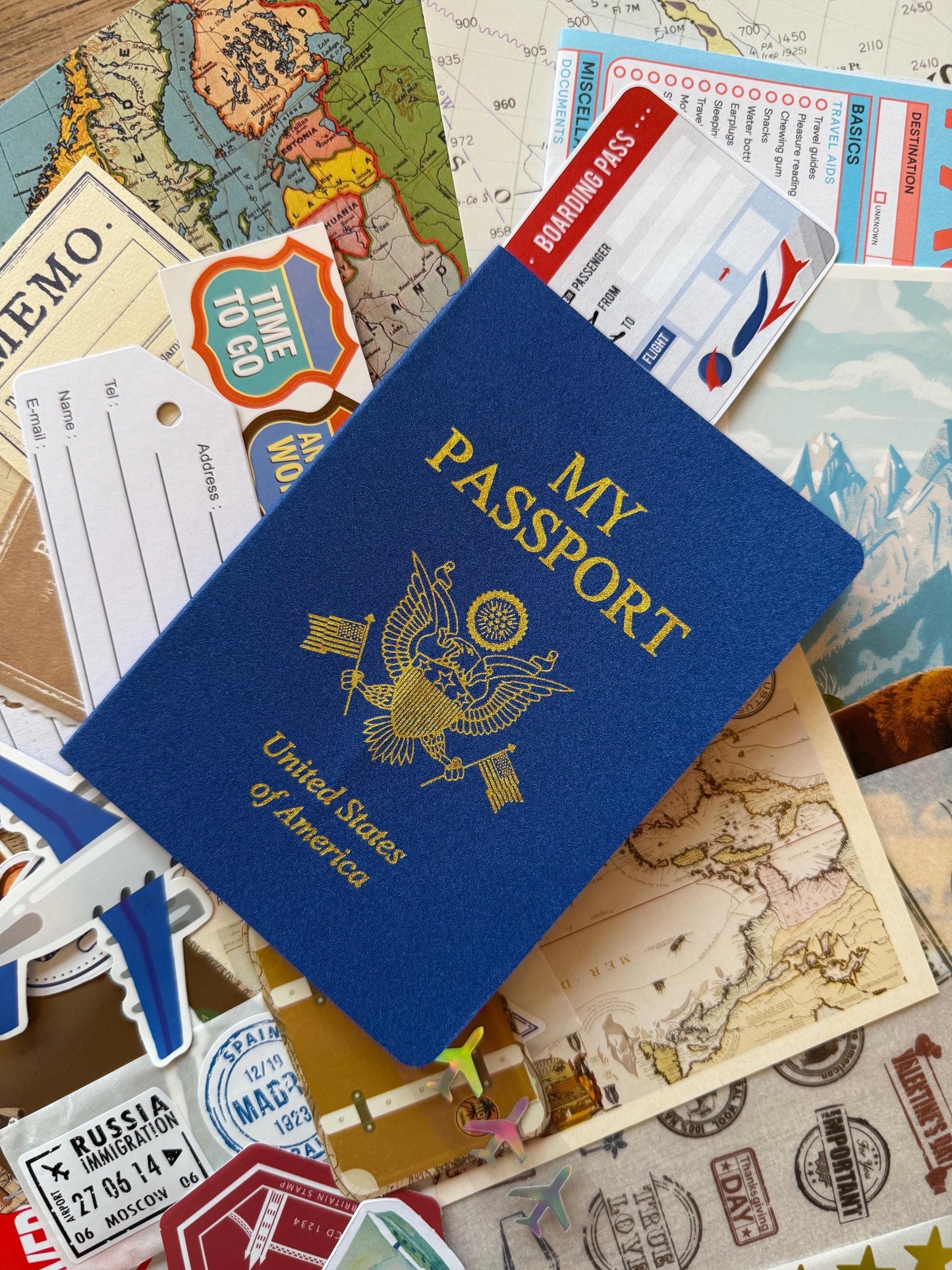 Travel-themed scrap pack with assorted ephemera including vintage tickets, postcards, maps, stamps, patterned papers, and travel-inspired stickers arranged neatly on a white background